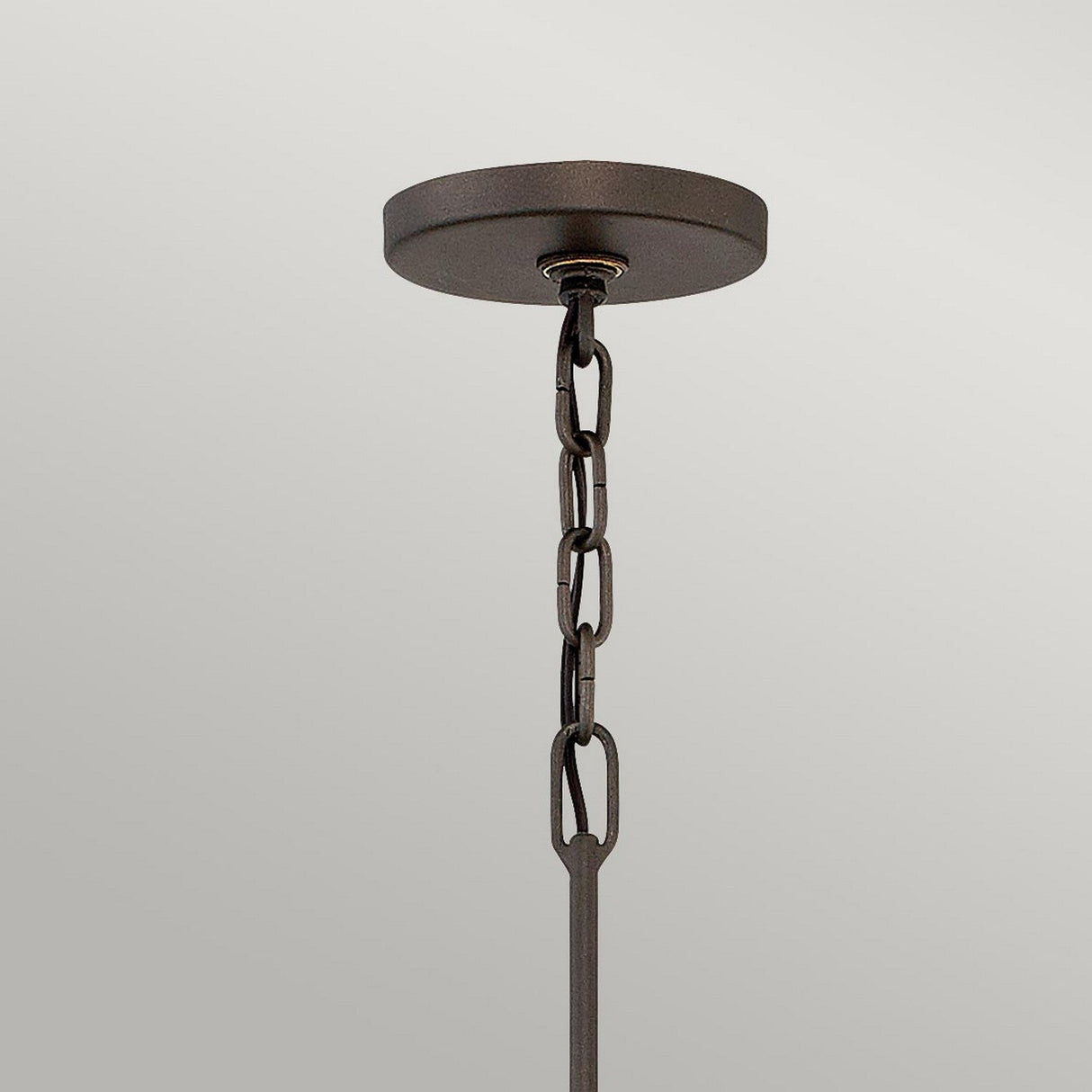 The Astrid 5 Light Chandelier - Matte Bronze & Gold showcases a striking dark metal design with a chain that gracefully extends downward, featuring a geometric outer cage. The matte bronze and gold finish is particularly eye-catching against the plain gray background.