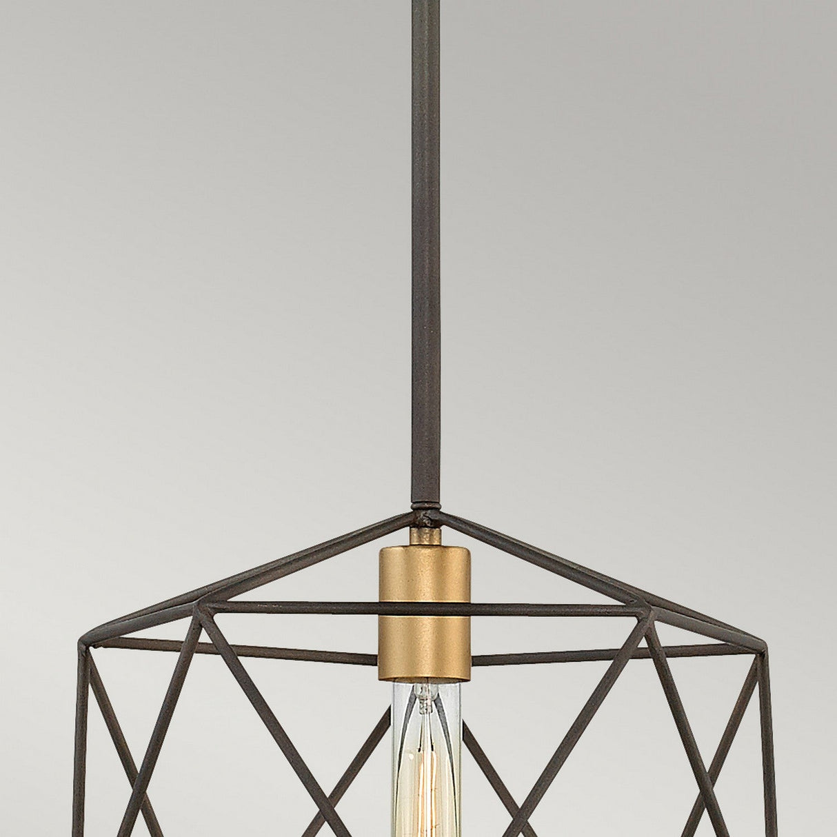 The Astrid Mini Pendant - Matte Bronze & Gold showcases geometric elegance with its matte bronze metal frame and exposed bulb, gracefully suspended from the ceiling. The dark finish of the frame beautifully contrasts with the gold-toned socket, set against a plain light grey background.