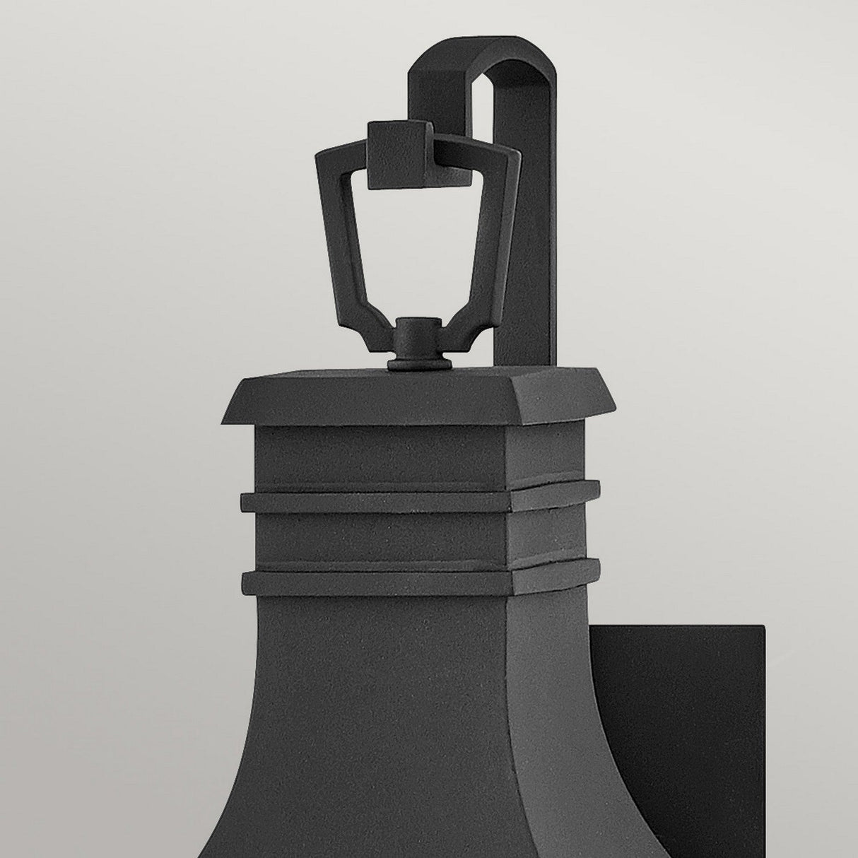 The Beacon Hill 1 Light Outdoor Small Wall Lantern in black showcases a rectangular backplate and curved base. Its sleek, geometric design is highlighted by seeded glass and topped with a handle, bringing elegance to its seamless installation on the light gray wall.