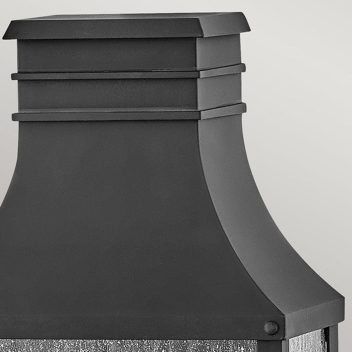 Close-up of an elegant, contemporary black structure with smooth lines and a minimalist aesthetic, reminiscent of the Beacon Hill 2 Light Outdoor Half Wall Lantern in Black. The design is set against a simple, light gray background, accentuating its polished surface and angular form.