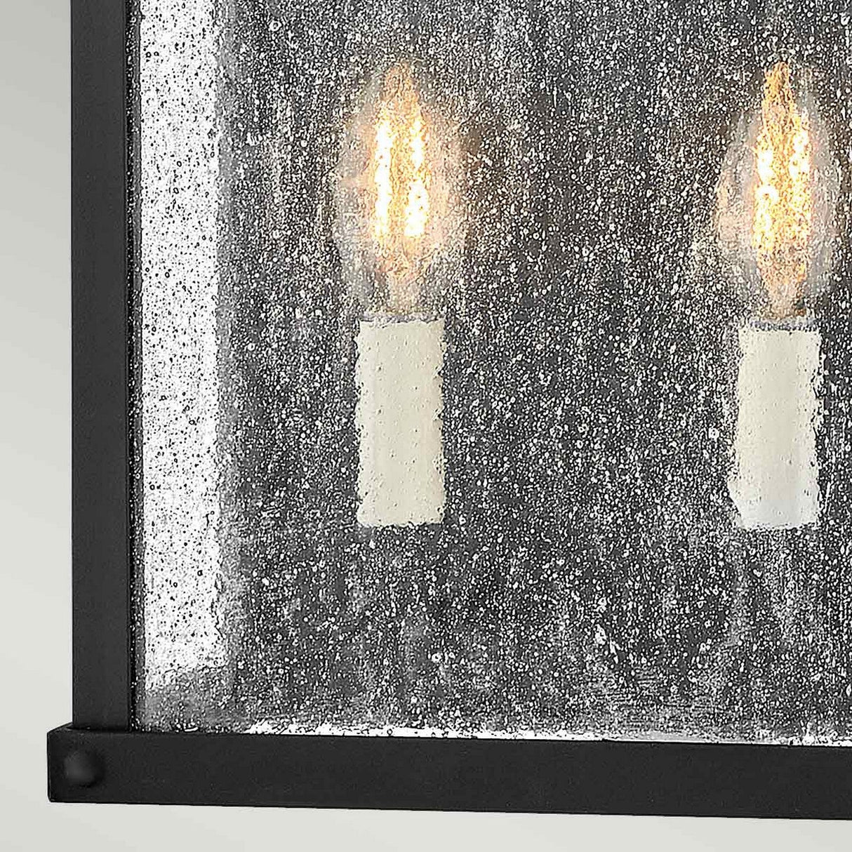 This close-up showcases the Beacon Hill 2 Light Outdoor Half Wall Lantern - Black, featuring two candle-style LED bulbs encased in a Museum Black Aluminum Frame. The lantern's rectangular design and textured glass panels exude elegance, embodying the timeless charm of the classic Beacon Hill style.