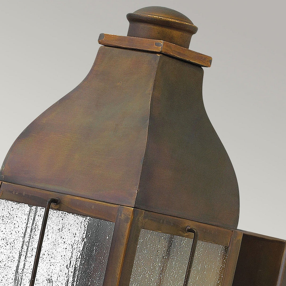 The Bingham 3 Light Outdoor Medium Wall Lantern in brown showcases a close-up of its nautical-inspired, vintage-style design. It has a square base and an elegantly arched top, featuring clear glass panels and a weathered finish, all set against a neutral background to capture its timeless charm.