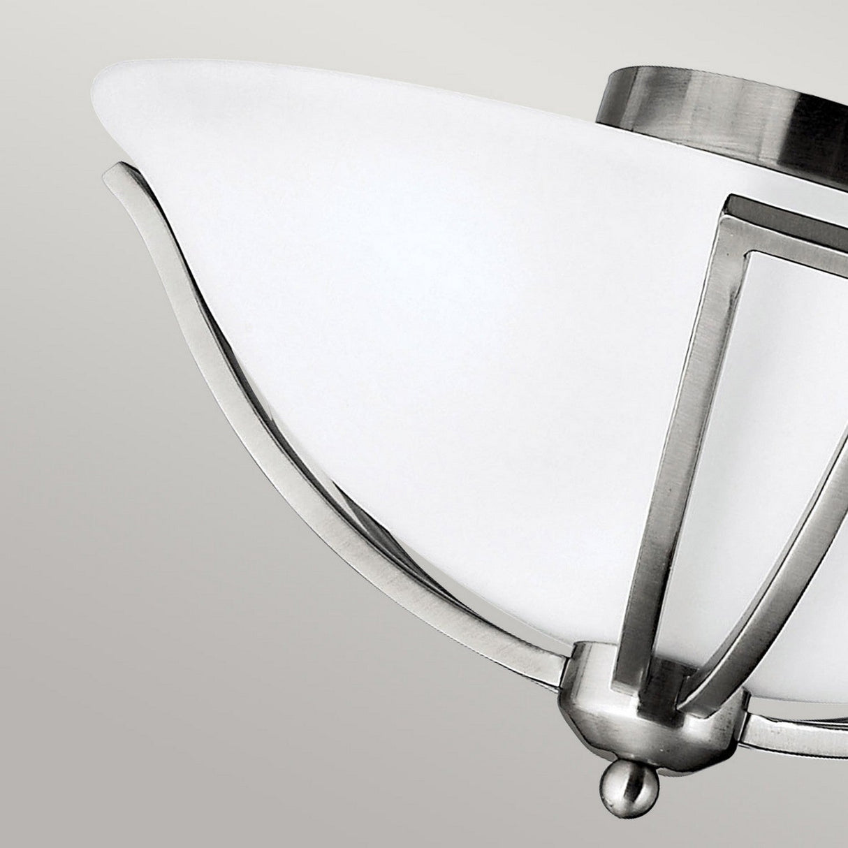 The image highlights the Bolla 2 Light Flush in Brushed Nickel, featuring a white curved glass shade and brushed nickel details against a gray setting. Its design is sleek and contemporary.
