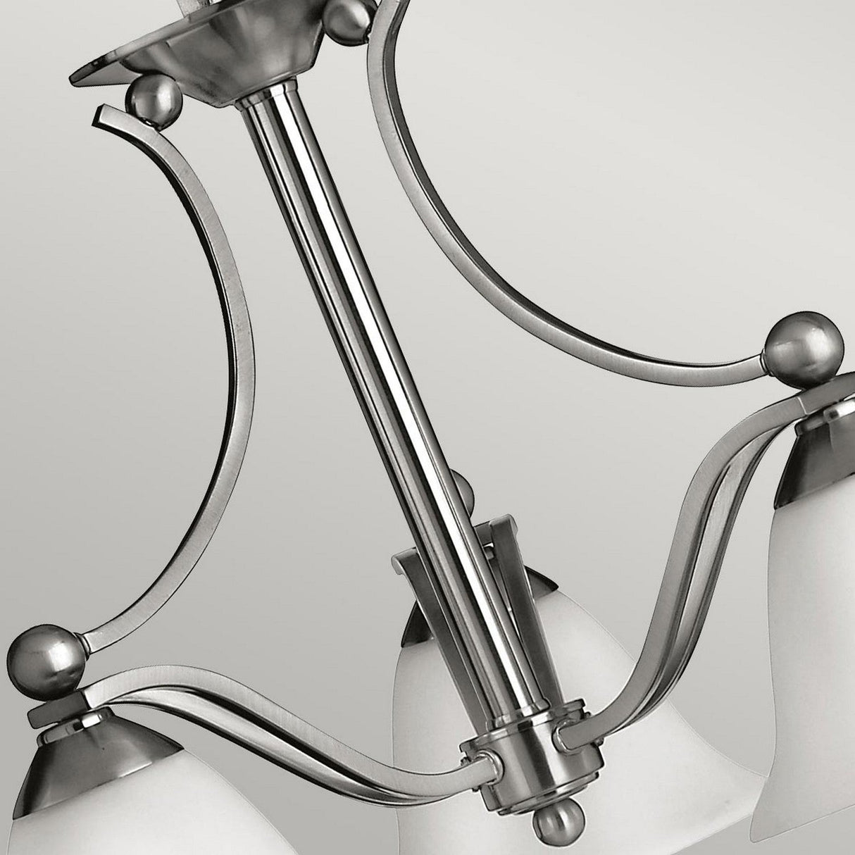 Presenting the Bolla 3 Light Chandelier in Brushed Nickel, this lighting fixture features three frosted glass shades complemented by elegantly curved arms. Its sleek and modern design contrasts beautifully against a plain background.