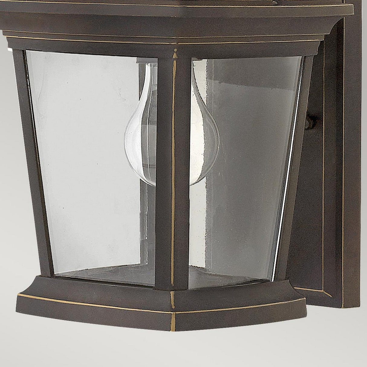 The Bromley 1 Light Outdoor Small Wall Lantern in bronze is made from die-casted aluminum and features clear glass panels with a visible bulb. This classic design includes subtle gold accents and a rectangular mounting plate, offering a blend of elegance and durability.