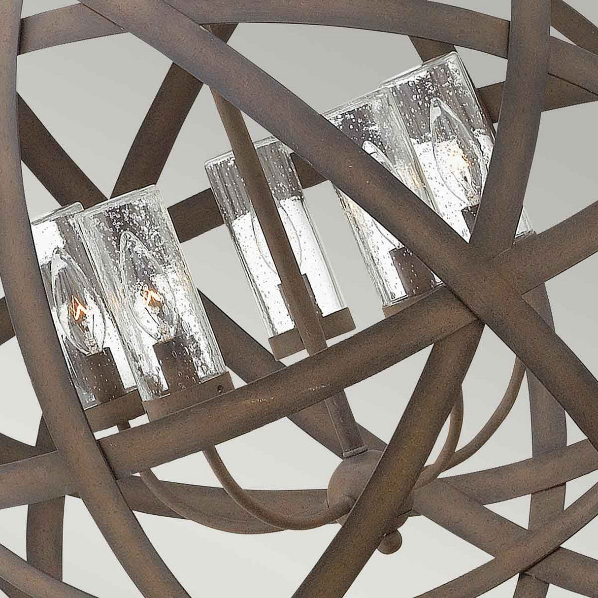 Detailed view of the Carson 5 Light Outdoor Chandelier in Vintage Iron, showcasing its intricate design with overlapping metal rings. It is equipped with several candle-like light fixtures set within textured glass covers, blending modern aesthetics with rustic charm.