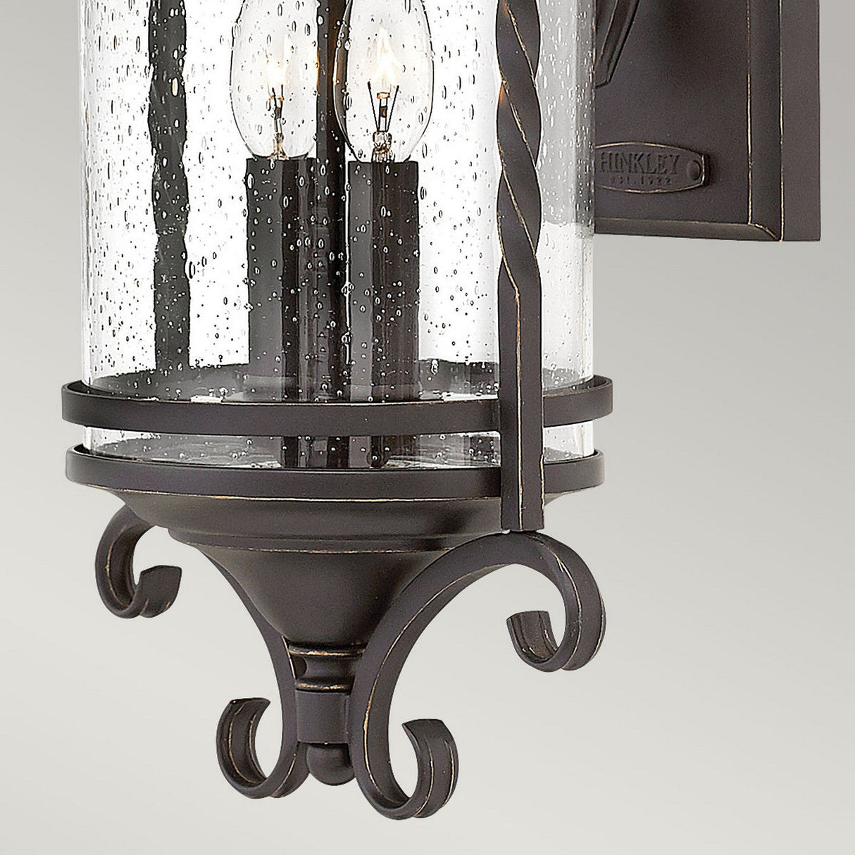 Introducing the Casa 2 Light Outdoor Wall Lantern, a timeless piece that exudes rustic charm. This elegant wall lantern features a sleek black finish and two candle-style lights encased in clear seeded glass, adorned with decorative scrollwork details reminiscent of exquisite wrought iron craftsmanship.