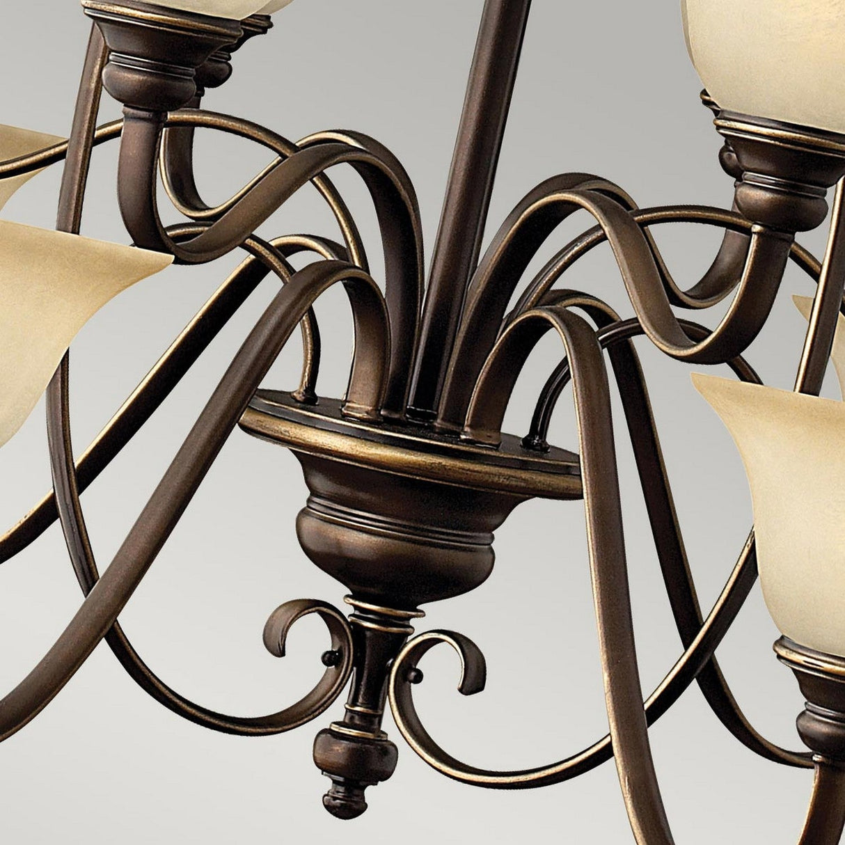 A close-up of the Cello 15 Light Chandelier in antique bronze, showcasing its ornate design. The chandelier boasts curved arms and vintage faux alabaster glass lampshades, perfectly blending classic and elegant design elements against a neutral backdrop.