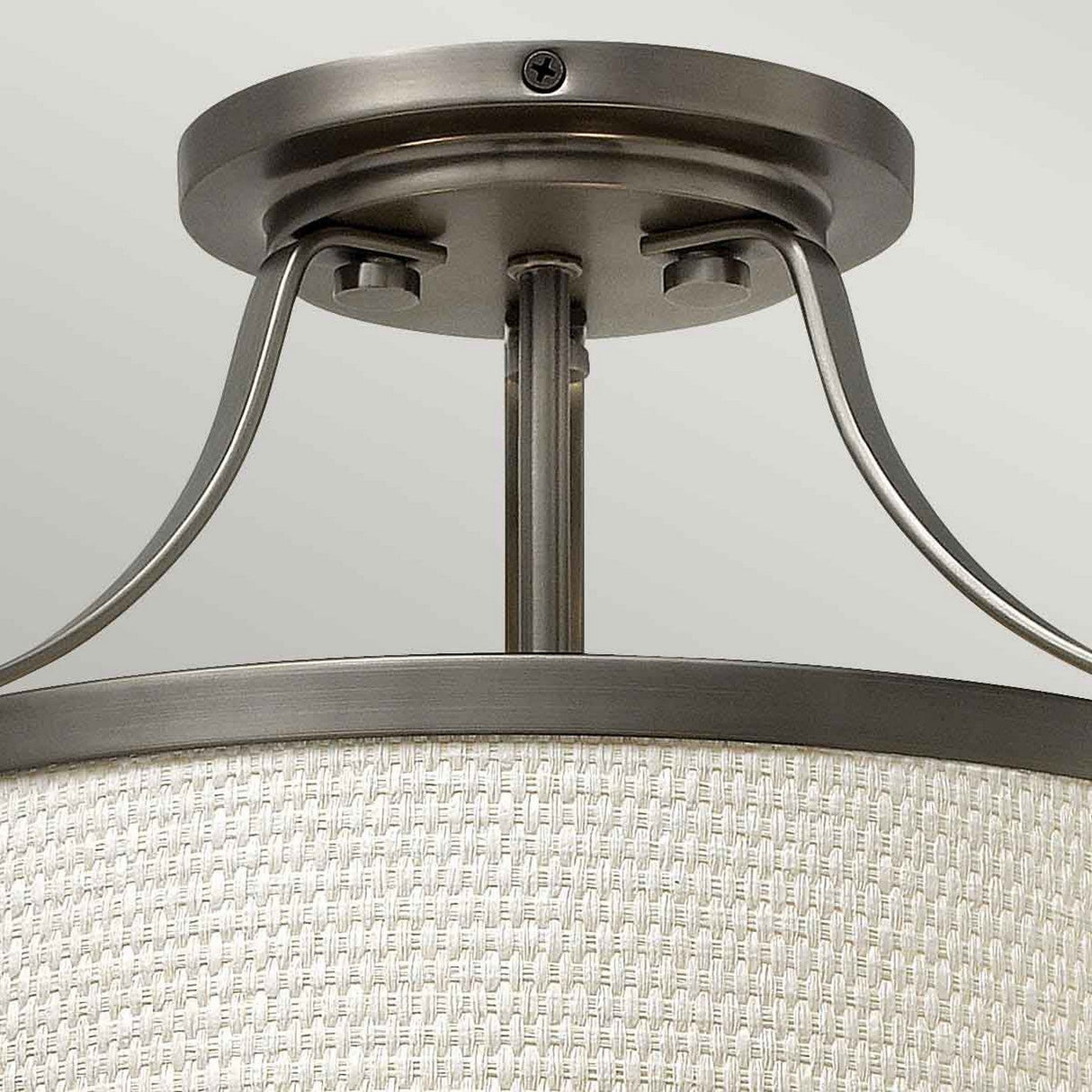Close-up of the Charlotte 3 Light Semi Flush ceiling fixture, featuring a cream-colored linen shade with a woven texture and metal supports in antique nickel. The fixture is elegantly mounted on a light green ceiling.