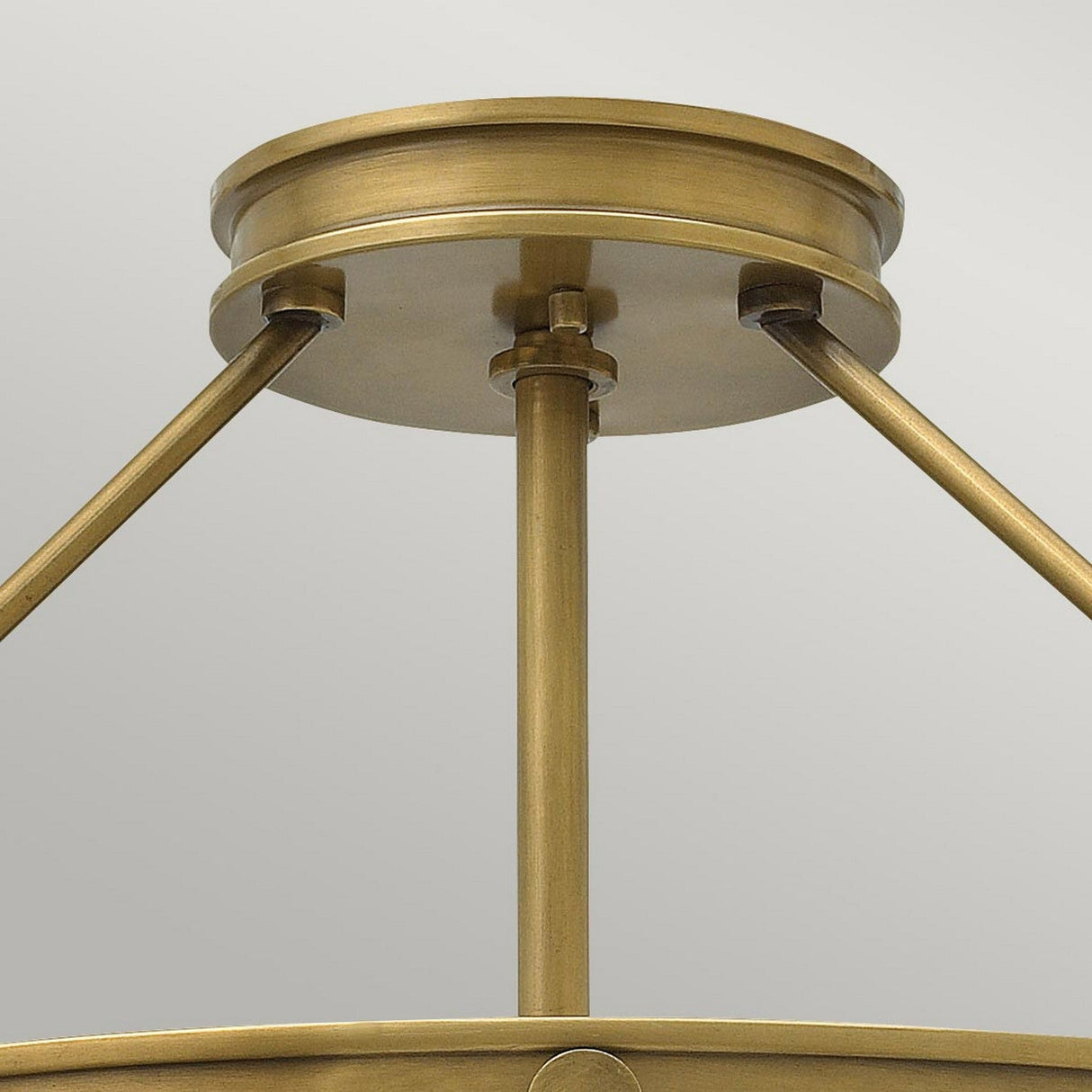 Close-up of the Collier 4 Light Large Semi Flush featuring a bronze-inspired ceiling fixture with a round canopy and three supporting rods connected to a central stem. Its brushed metallic finish in Heritage Brass enhances its simple, modern design.