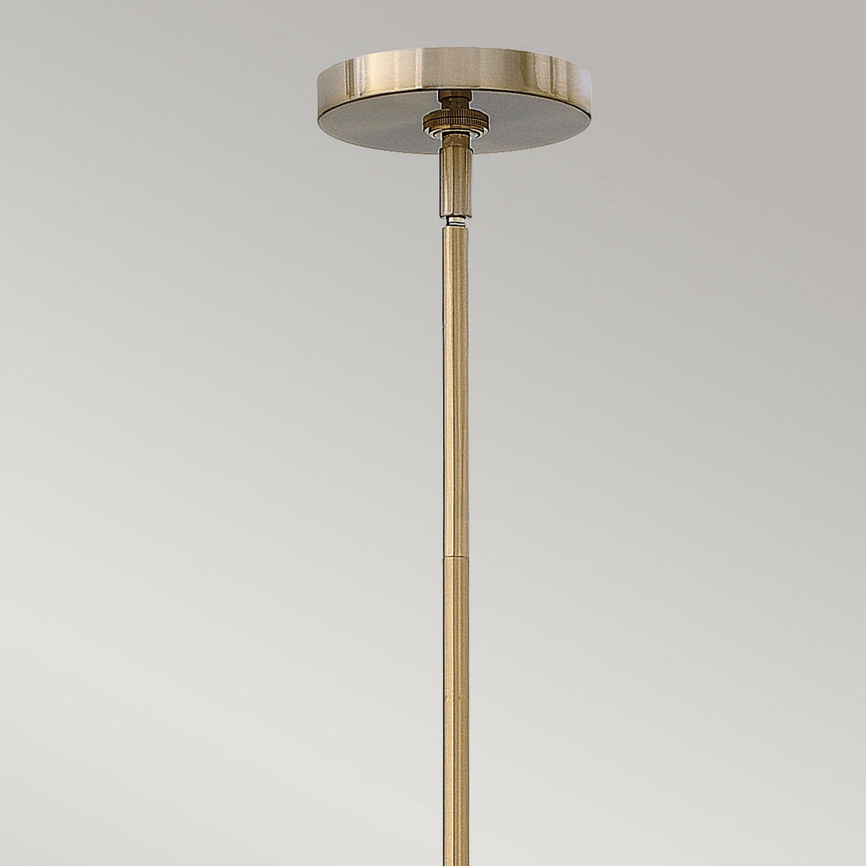 Against a light gray background, the ceiling-mounted rod in a brass-tone finish supports the Congress 4 Light Clear Glass Chandelier in Brushed Caramel, introducing a vintage accent to the room.