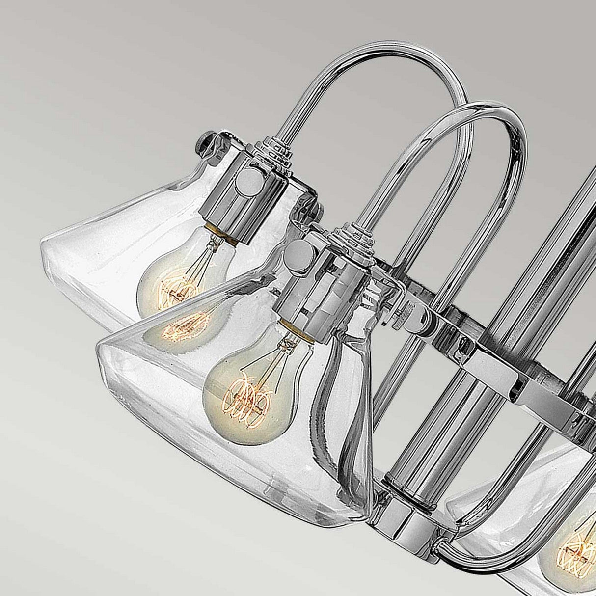 Featuring the Congress 4 Light Clear Glass Chandelier in chrome, this elegant light fixture showcases clear glass shades and visible filament bulbs. The chrome finish enhances its curved metal design, while two bulbs are prominently displayed, exuding a contemporary and industrial vibe.