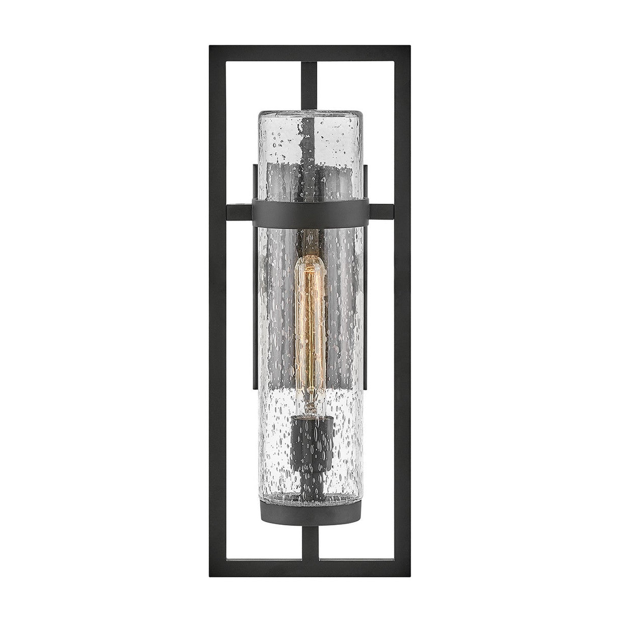 The Cordillera 1 Light Outdoor Wall Light in black showcases a contemporary design with a rectangular metal frame that encases a cylindrical glass cover. Its visible filament bulb contributes to the industrial-chic aesthetic, while the bubble-like textured glass adds to its stylish charm.