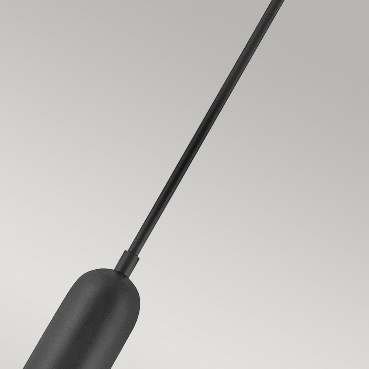 Close-up of a minimalist Dax LED Mini Pendant in black against a light gray background. The image highlights the pendant's slender vertical stem and elongated oval base, delivering energy-efficient illumination with its elegant, contemporary design. A true modern lighting fixture that enhances the sophistication of any space.