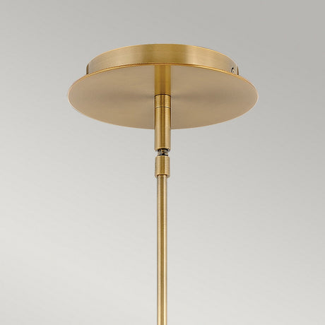 A close-up of the Dax LED Mini Pendant in Heritage Brass, featuring a round ceiling mount and a sleek, straight rod extending downward against a plain gray background, embodies energy-efficient lighting.