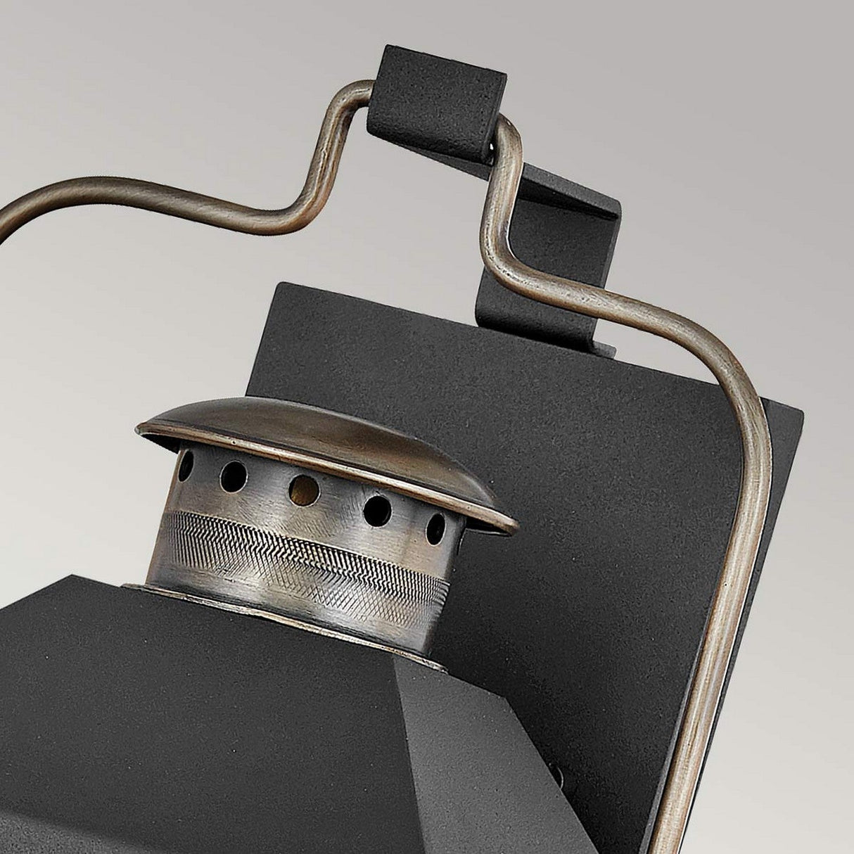 Close-up of an industrial charm lighting piece: the Fitzgerald 2 Light Outdoor Medium Wall Lantern in black with burnished bronze, featuring a vintage-style design with an intricate handle and perforated chimney top, set against a neutral background. This elegant outdoor wall lantern seamlessly blends classic design with modern functionality.