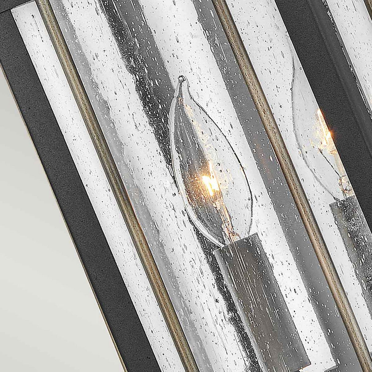 Featuring the Fitzgerald 2 Light Outdoor Medium Wall Lantern in Black with Burnished Bronze, this lantern showcases sleek, textured glass with droplet patterns for a vintage and elegant appearance. Its lit bulbs emit a soft glow within a modern metallic frame, seamlessly blending industrial charm with timeless appeal.