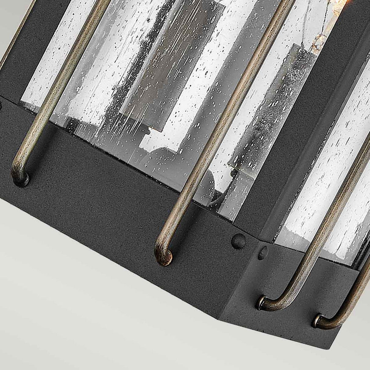 A close-up of the Fitzgerald 2 Light Outdoor Medium Wall Lantern in black with burnished bronze shows off its industrial charm and modern appeal. This outdoor light features a black metal frame with clear glass panels, enhanced by a visible raindrop texture that complements its IP44 rating. Vertical metal bars add to the intricate design details, completing its stylish look.