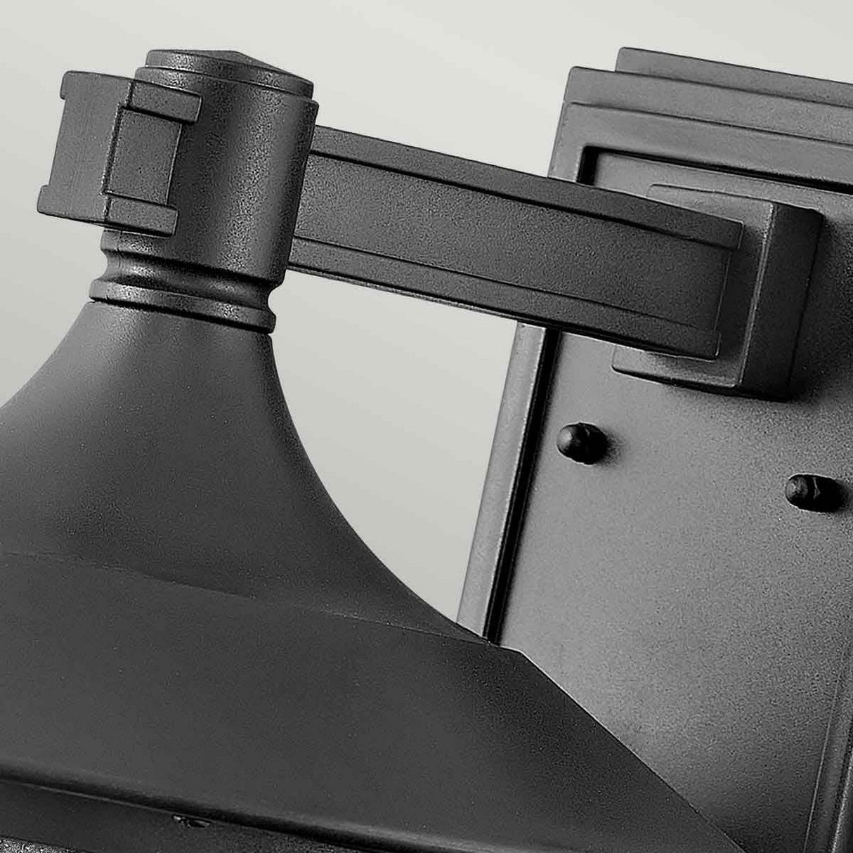 Here is a description of the product using the provided data:
A detailed view of the Freeport 1 Light Outdoor Large Wall Lantern in black, showcasing its weather-resistant properties. The lantern features a sleek, modern design with a rectangular backplate and a cylindrical arm that extends to support a conical shade.