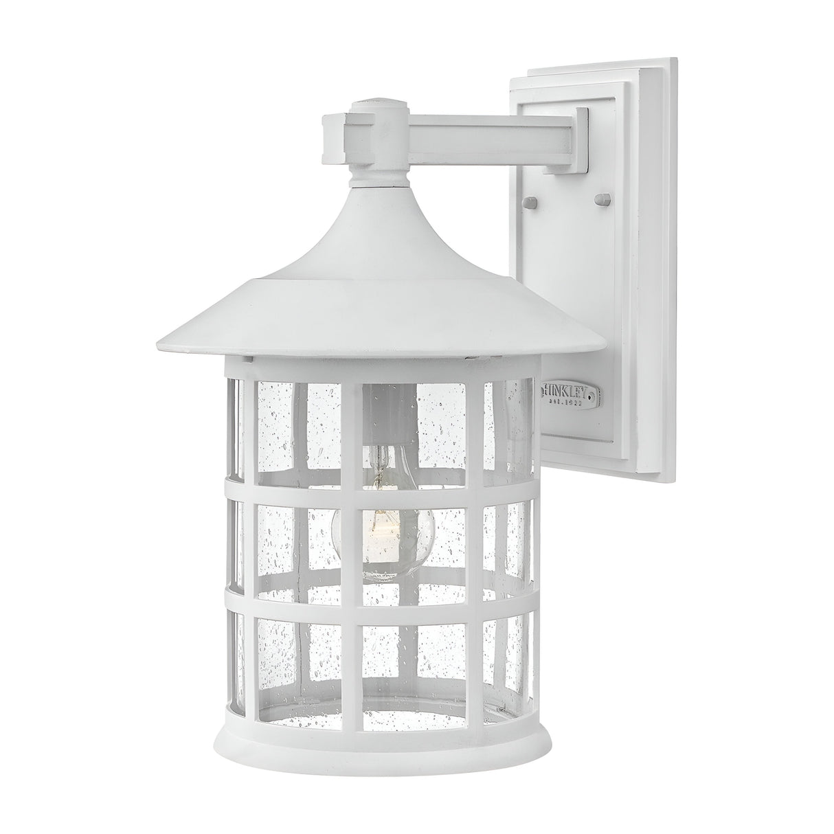 The Freeport 1 Light Outdoor Large Wall Lantern in white is a durable and weather-resistant outdoor fixture featuring a circular enclosure of clear seeded glass with a grid pattern, topped by a metal roof. It is mounted on a rectangular backplate, showcasing a visible bulb inside.