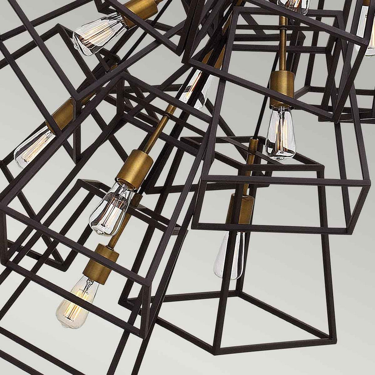 The Fulton 13 Light Large Chandelier encapsulates a cluster of geometric pendant lights featuring exposed bulbs and exuding vintage industrial charm. Its open, cube-shaped frames accented with bronze and brass details contribute to a modern and artistic statement akin to a chandelier-like design.