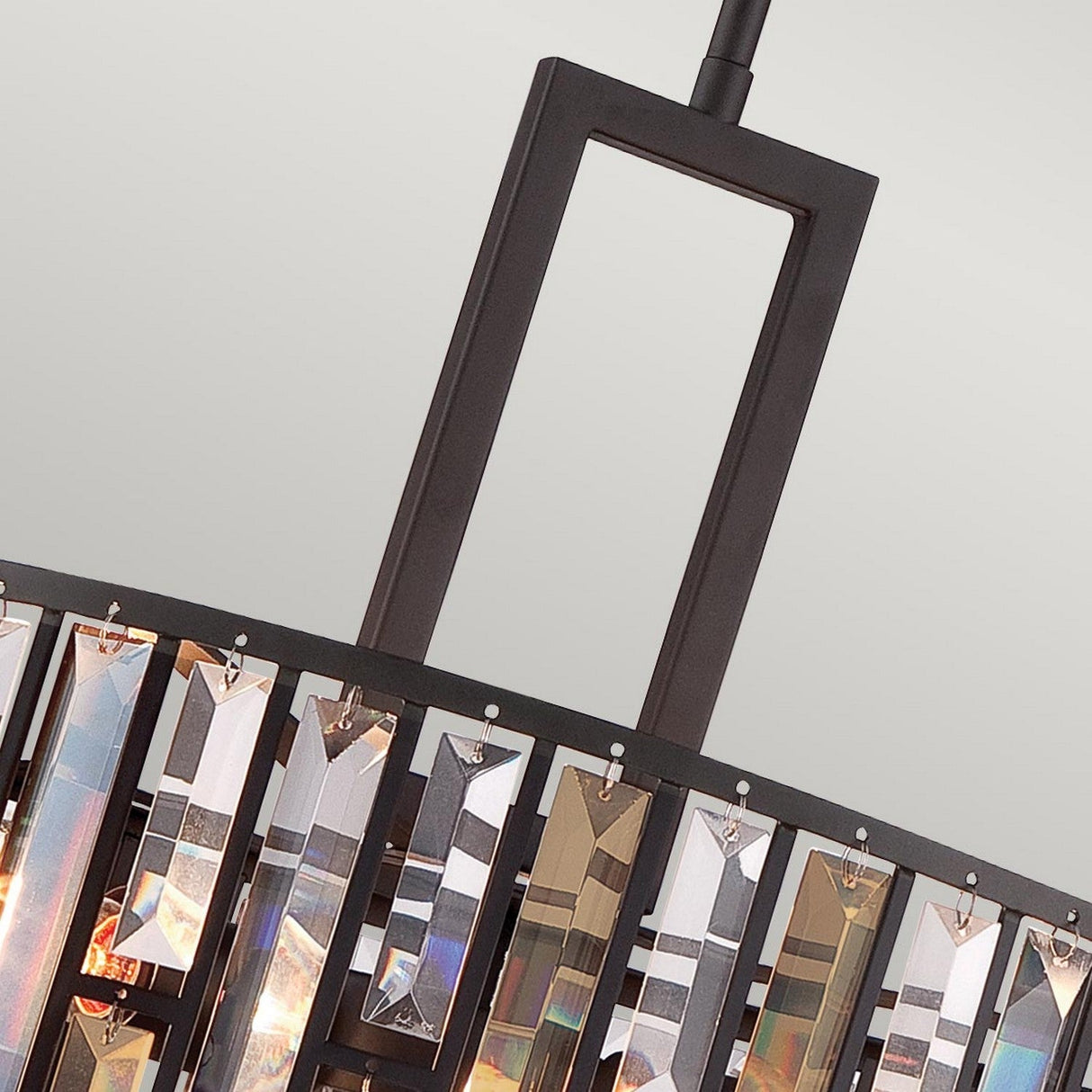 Close-up of the Gemma 3 Light Chandelier - Vintage Bronze, showcasing its contemporary design with a rectangular black frame. It features reflective geometric glass pieces that hang down to create a prism effect, set against a plain light gray background, combining modern style with vintage bronze elegance.