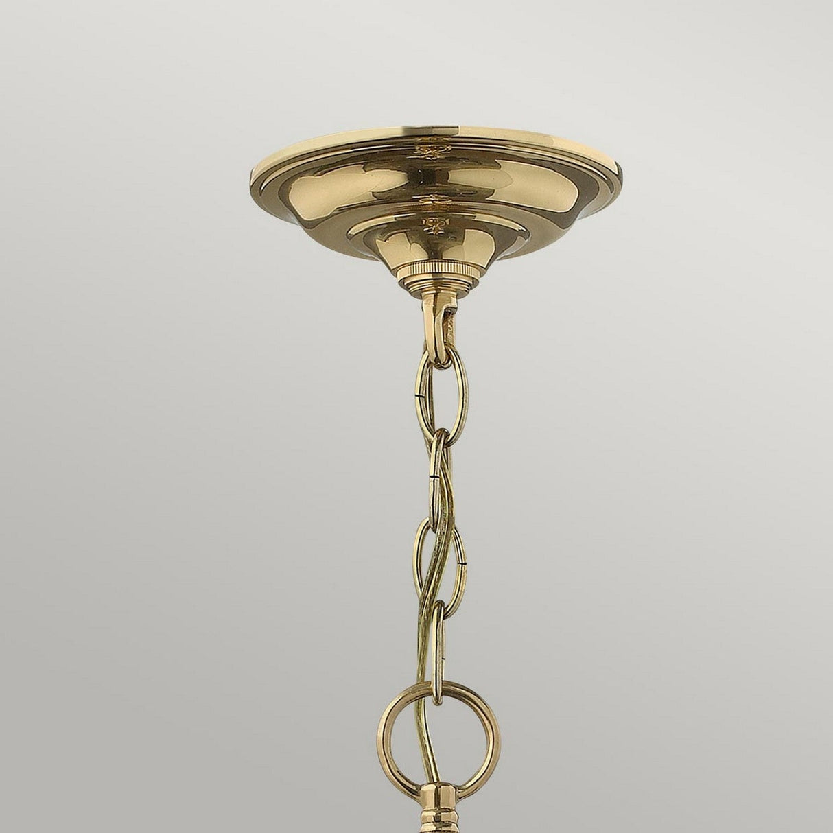 The Gentry 6 Light Large Pendant in polished brass hangs vertically with a decorative chain, showcasing a traditional design. The gleaming brass links stand out elegantly against the neutral light gray background, creating an exquisite contrast.
