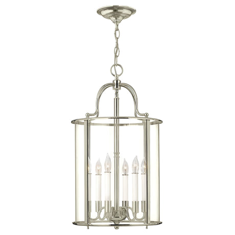 The Gentry 6 Light Large Pendant - Polished Nickel is a modern chandelier featuring clear bent glass panels. Its sleek design, complete with six candle-style bulbs elegantly suspended from a chain, adds a touch of sophistication to dining or living spaces.