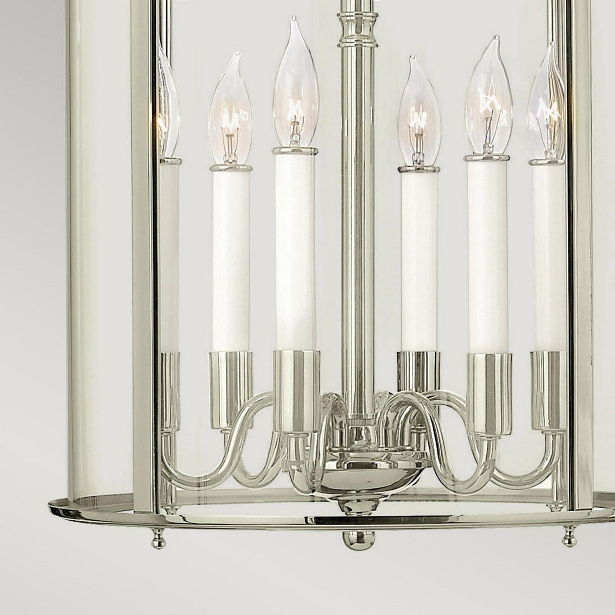 A close-up of the sophisticated Gentry 6 Light Large Pendant - Polished Nickel showcases its six candle-like bulbs and clear bent glass panels against a light gray background, enhancing its elegant charm.