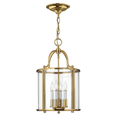 The Gentry 4 Light Medium Pendant in polished brass showcases a timeless design with clear bent glass panels that enclose four candle-shaped bulbs, delivering an elegant and classic aesthetic.