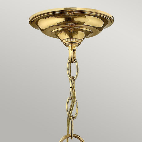 A detailed view of the Gentry 4 Light Medium Pendant in polished brass, featuring a decorative chain. This traditional design highlights clear bent glass panels, exuding elegance against a light gray backdrop.