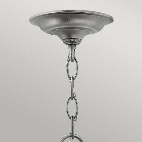 Close-up of the Gentry 4 Light Medium Pendant in brushed silver, featuring a chain extending downward. The chain elegantly passes through the loop, accentuating its sophisticated design with clear bent glass panels, creating an exquisite silhouette against a plain light gray background.