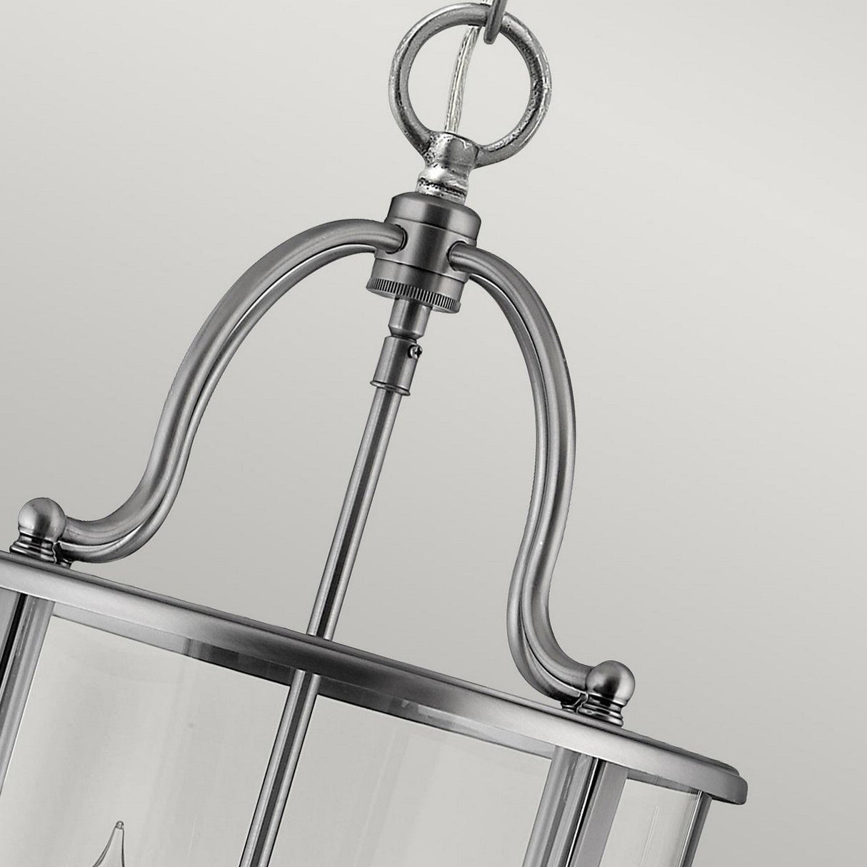 Close-up of the Gentry 4 Light Medium Pendant - Silver, featuring a sleek pendant frame and clear bent glass panels, elegantly suspended from a looped chain. The modern design is prominent against a light gray background.