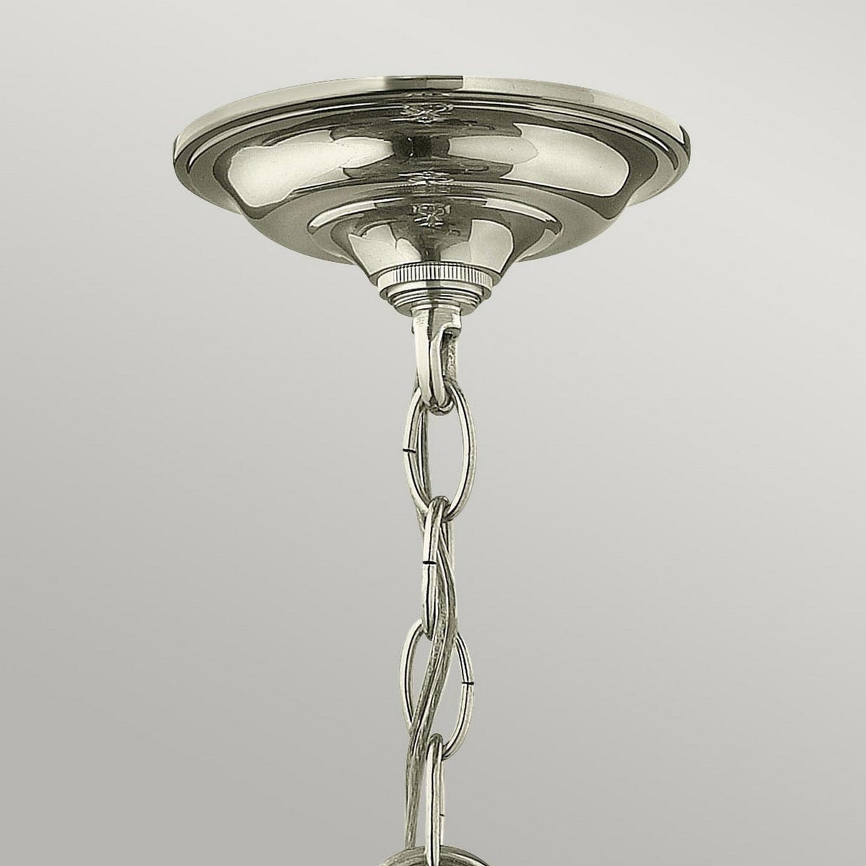 A close-up of the Gentry 3 Light Small Pendant in a polished nickel finish showcases its metallic ceiling mount. A decorative metal chain extends downward, designed for hanging the small pendant, against a light gray background.