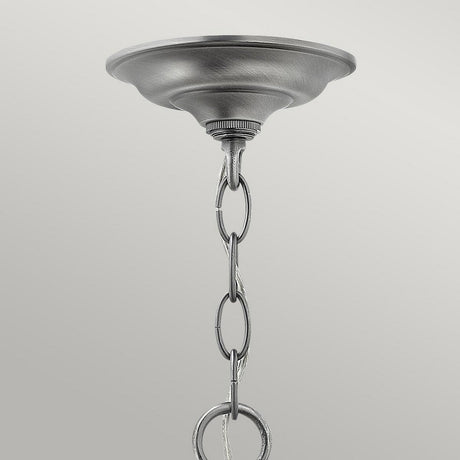 A close-up of the Gentry 3 Light Small Pendant - Silver features a decorative mounting plate and striking silver finish. The chain, adorned with interlocking oval links, elegantly extends downward. With clear bent glass panels, this pendant stands out against a simple light gray background.