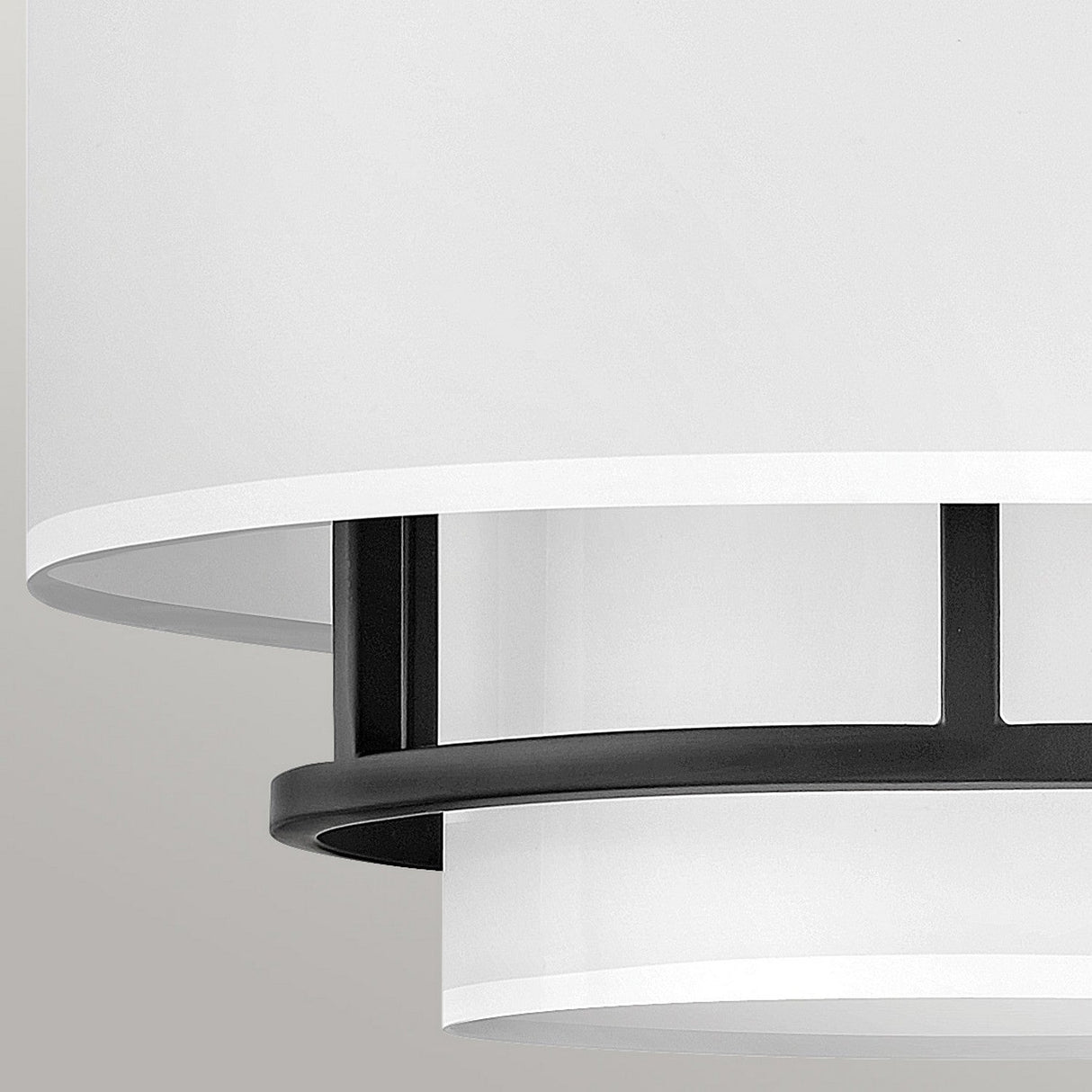 A detailed view of the Graham 3 Light Duo-Mount Pendant/Semi-Flush - Black highlights its contemporary ceiling light design featuring a white cylindrical shade complemented by black metal details. The bright faux parchment forms streamlined, layered circular elements set against a neutral background, achieving a minimalist aesthetic.