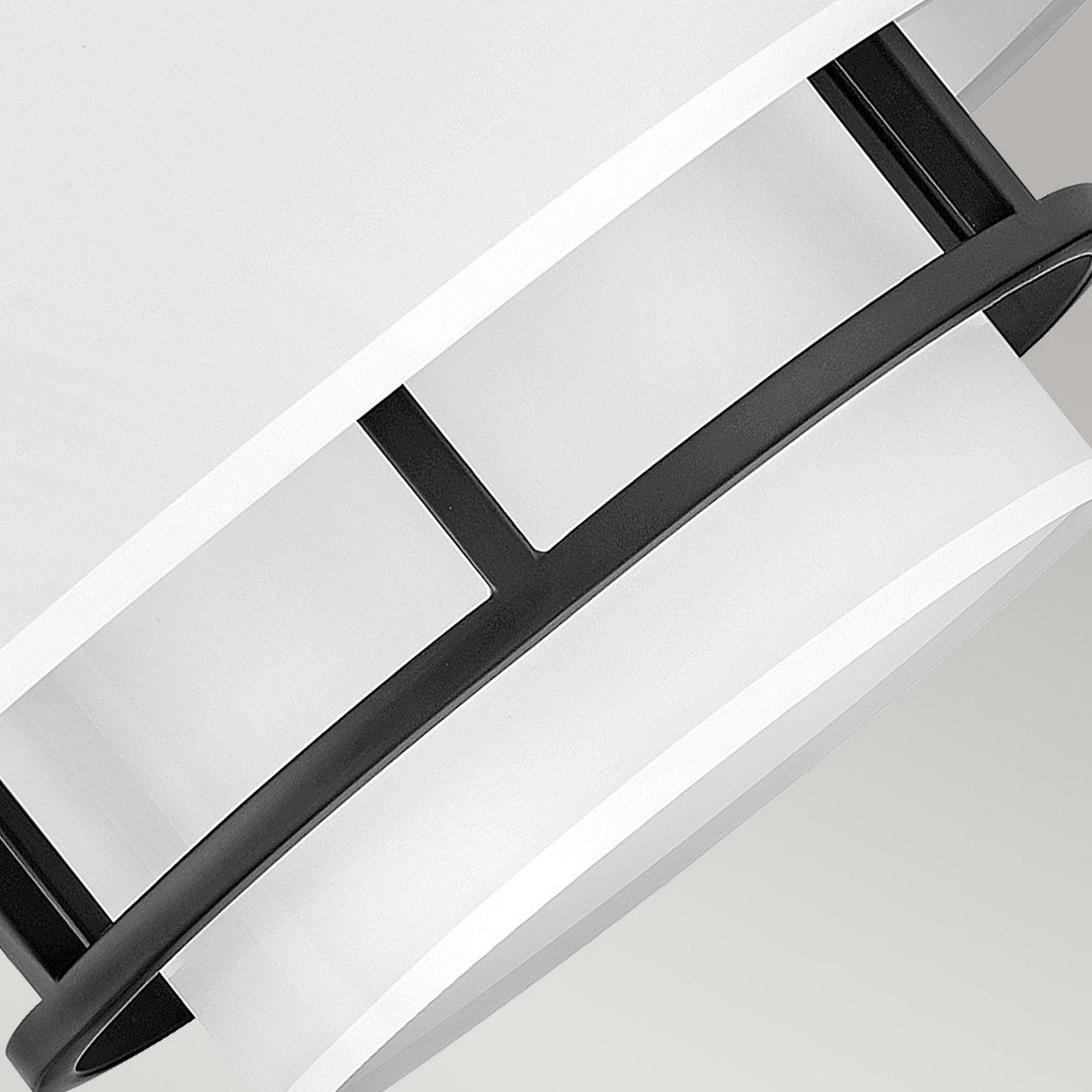 A close-up of the Graham 3 Light Duo-Mount Pendant/Semi-Flush - Black, showcasing its modern ceiling light fixture design. It features a white drum-shaped shade adorned with elegant black metal bands and a sleek black welded frame, exuding a contemporary aesthetic against a soft gray background.