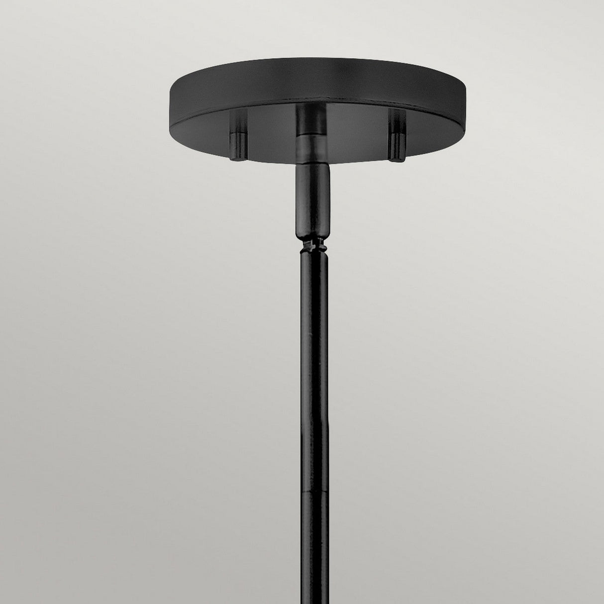 A close-up of the Graham 3 Light Duo-Mount Pendant/Semi-Flush – Black, featuring a black cylindrical rod extending downwards and highlighted against a plain gray background, demonstrates its sleek design within the black welded frame.