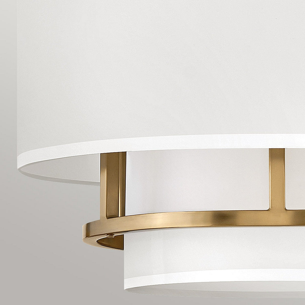 Here's a close-up of the Graham 3 Light Duo-Mount Pendant/Semi-Flush - Lacquered Brass, a modern ceiling fixture with versatile dual-mount capability. This piece showcases a cylindrical white shade elegantly accented by a lacquered brass ring, exemplifying a minimalistic and contemporary design.