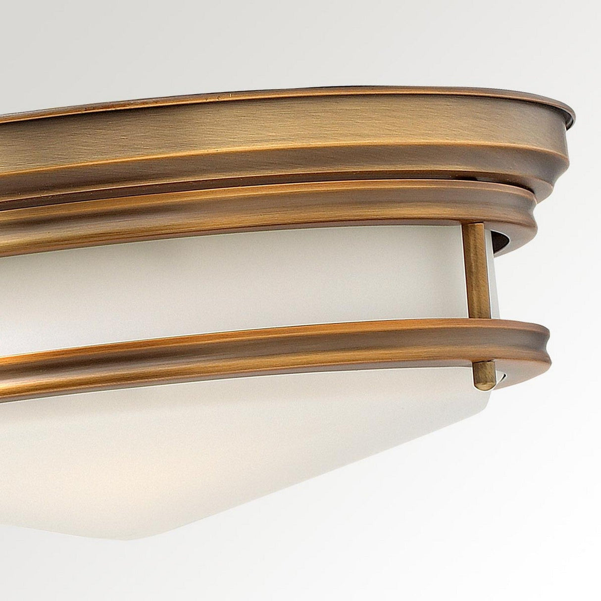 Close-up of the Hadley 3 Light Flush - Brushed Bronze, showcasing its modern ceiling light fixture with a frosted glass shade and brushed bronze-colored metal frame. The sleek, circular design features multiple layers and a smooth finish, offering a hint of vintage-inspired lighting elegance.