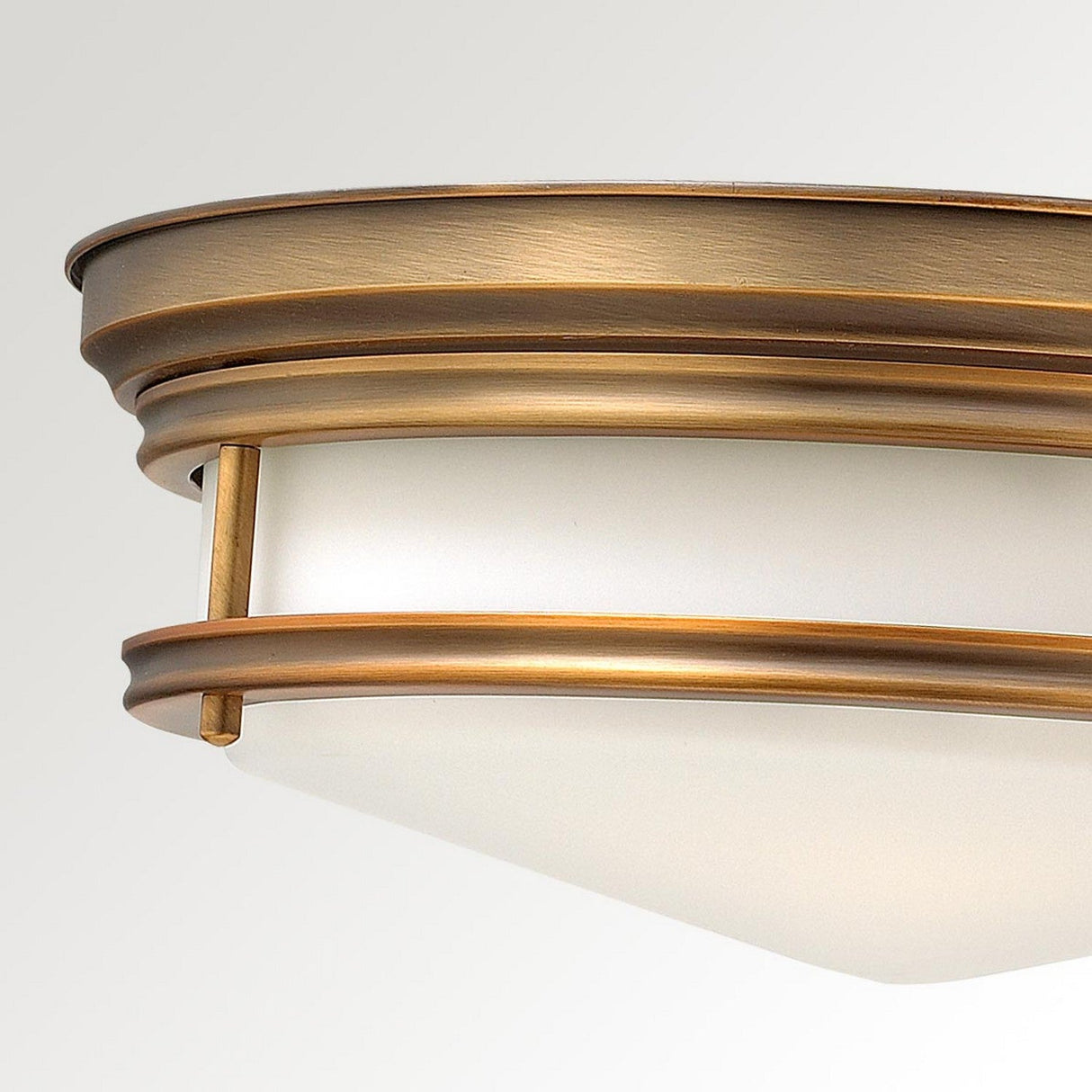 Close-up of the Hadley 3 Light Flush ceiling fixture in brushed bronze, featuring a frosted glass shade and a modern, minimalist design with vintage-inspired elements.