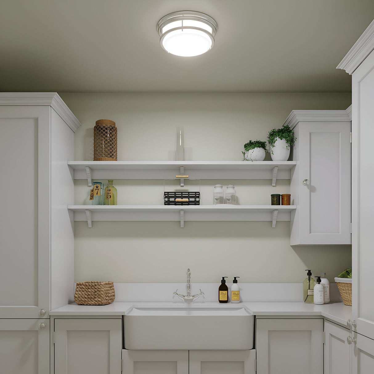 A tidy, modern laundry room showcases white cabinets and a farmhouse sink. Two white shelves display decor items, plants, and laundry supplies. The space is illuminated by a Hadley 3 Light Flush - Chrome fixture with an etched opal glass shade, adding a touch of elegance to the ceiling.