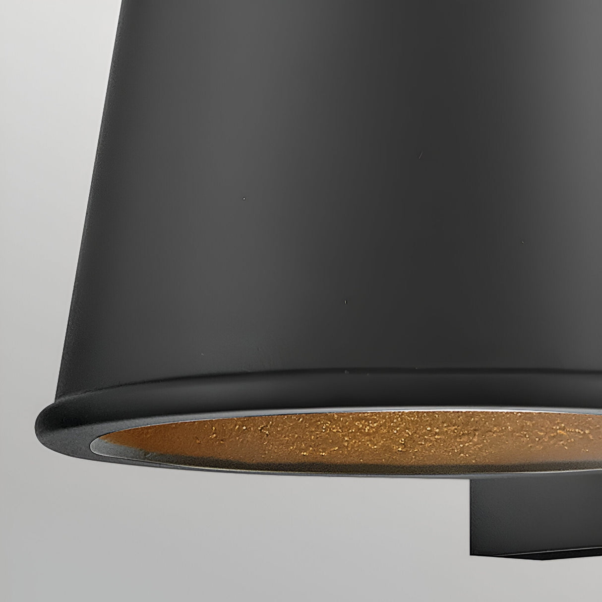 Close-up of the Coastal 1 Light Small Outdoor Wall Lantern in textured black finish, featuring a gold-colored inner lining. The partially visible lamp is set against a neutral, light background.