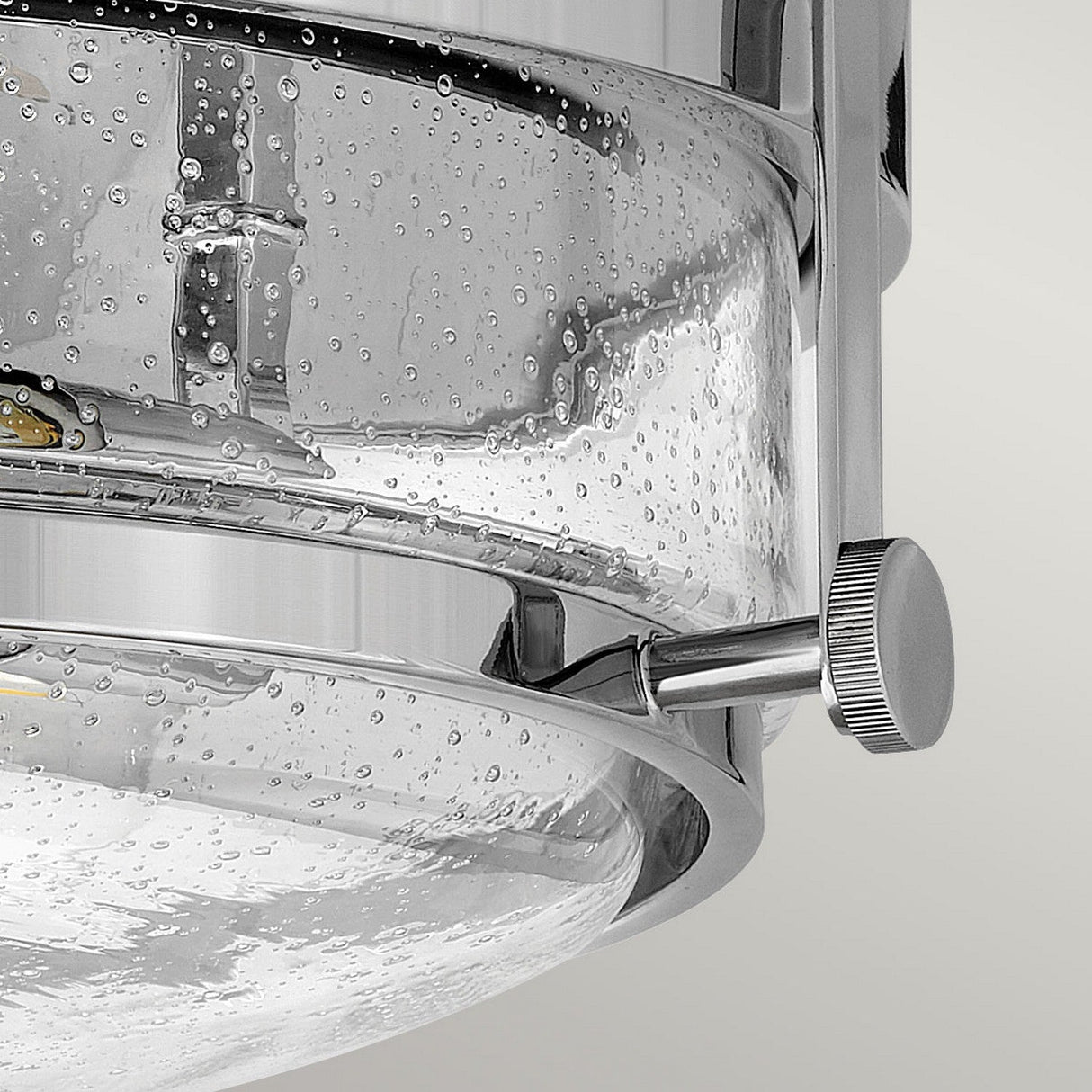 Close-up of the Harper 3 Light Flush in polished chrome, showcasing a modern cylindrical design with a clear seeded glass shade that provides a bubble texture, accentuated by a metal adjustment knob on the side.
