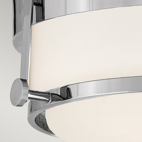 A close-up of the Harper 3 Light Flush - Polished Chrome With Opal Etched Glass showcases a sleek, cylindrical ceiling light fixture with an opal etched glass shade and a small knurled adjustment knob on the side.