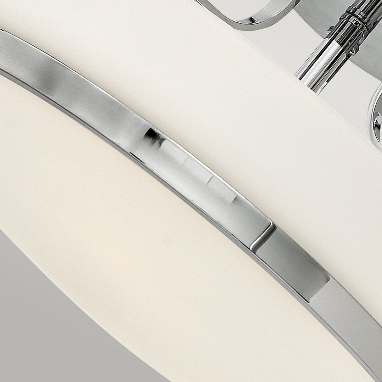 Featuring a close-up of the Harper 3 Light Medium Semi Flush, this modern light fixture highlights its sleek polished chrome finish and opal etched glass shade. Its minimalist design and smooth curves embody a contemporary aesthetic set against a neutral background.