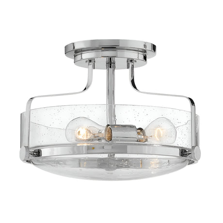 The Harper 3 Light Small Semi Flush in polished chrome showcases a sleek circular design equipped with three bulbs, all beautifully enclosed within clear seeded glass, and is elegantly supported by a simple cylindrical base.