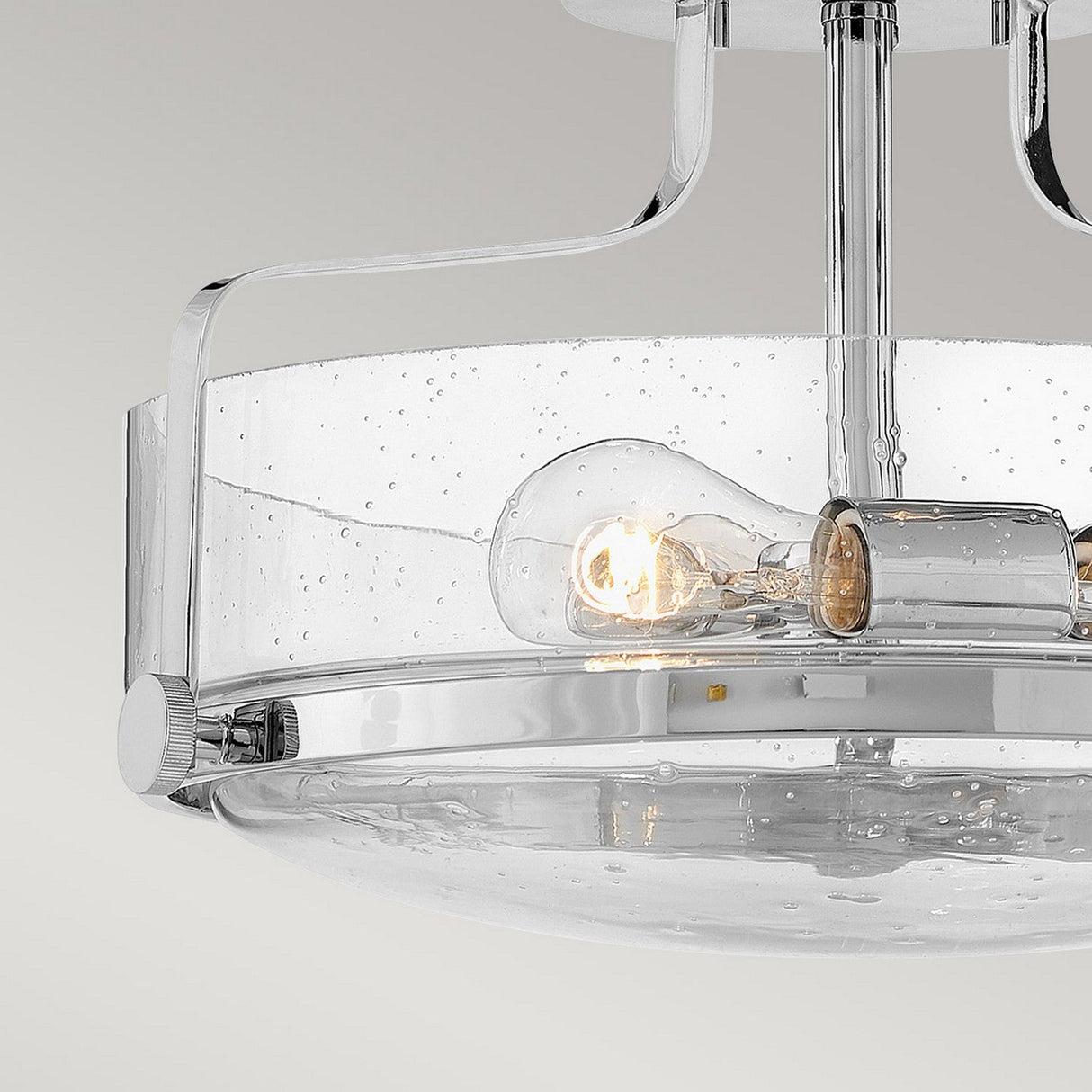 Introducing the Harper 3 Light Small Semi Flush in polished chrome, featuring clear seeded glass shades with water droplet textures. This modern ceiling light fixture houses two visible LED bulbs and embodies a minimalist design with its sleek metallic accents.