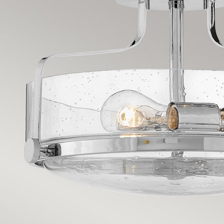Introducing the Harper 3 Light Small Semi Flush in polished chrome, featuring clear seeded glass shades with water droplet textures. This modern ceiling light fixture houses two visible LED bulbs and embodies a minimalist design with its sleek metallic accents.