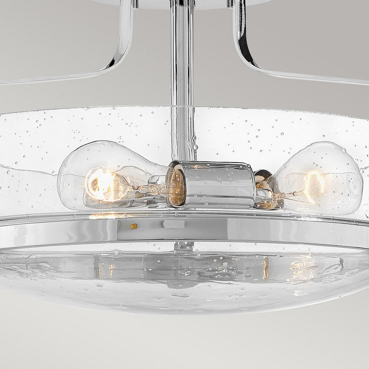 Product close-up of the Harper 3 Light Small Semi Flush, featuring two exposed bulbs within a clear, seeded glass dome. The fixture is elegantly finished in polished chrome, and the glass is adorned with small bubble-like patterns for enhanced appeal.